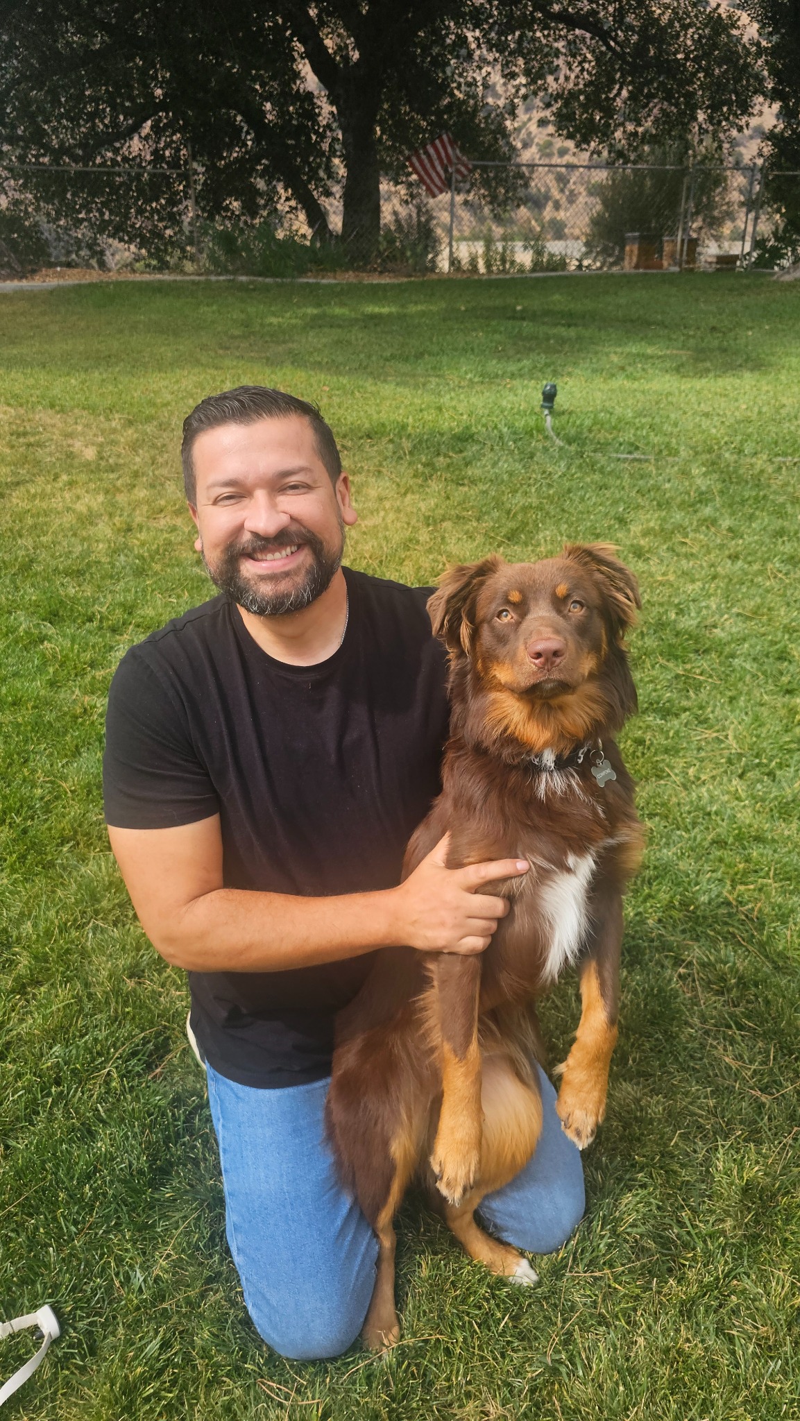 Jason Castillo smiling outdoors with his dog, Cowpoke